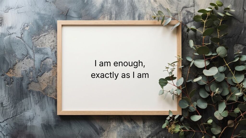 Wooden frame surrounded by eucalyptus leaves showcasing self love quotes for women.