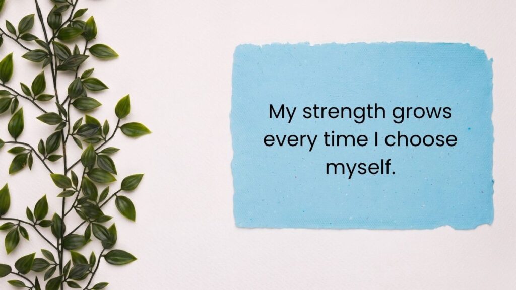 Blue paper note beside green leafy vine displaying self love quotes for women.